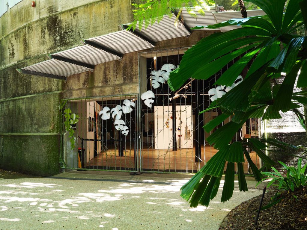 Gallery space within Tanks Arts Centre, showcasing artwork and installations, with the historical tank structure and rainforest integration visible outside."