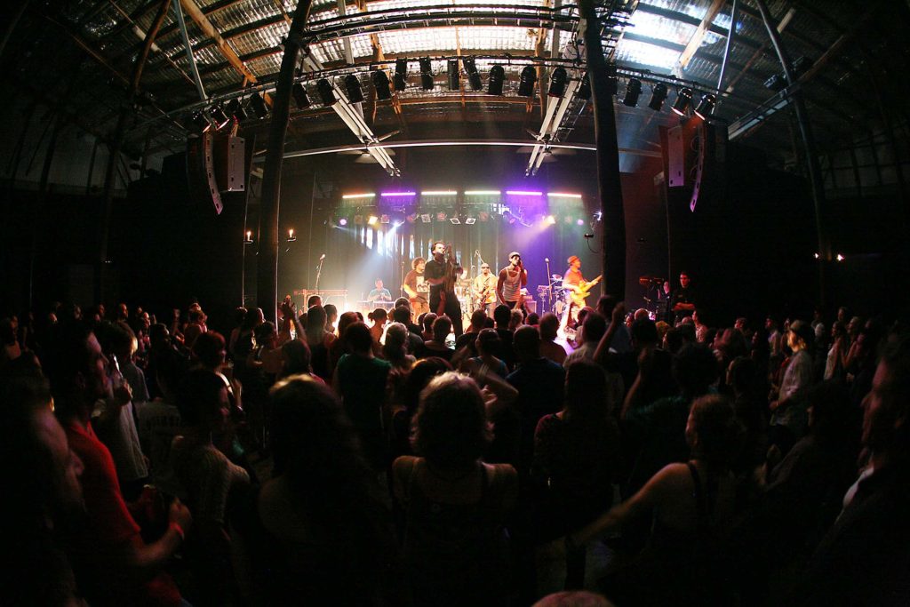 A large crowd enjoying a performance at Tanks Arts Centre, demonstrating the vast internal space and cultural vitality of the repurposed tank.