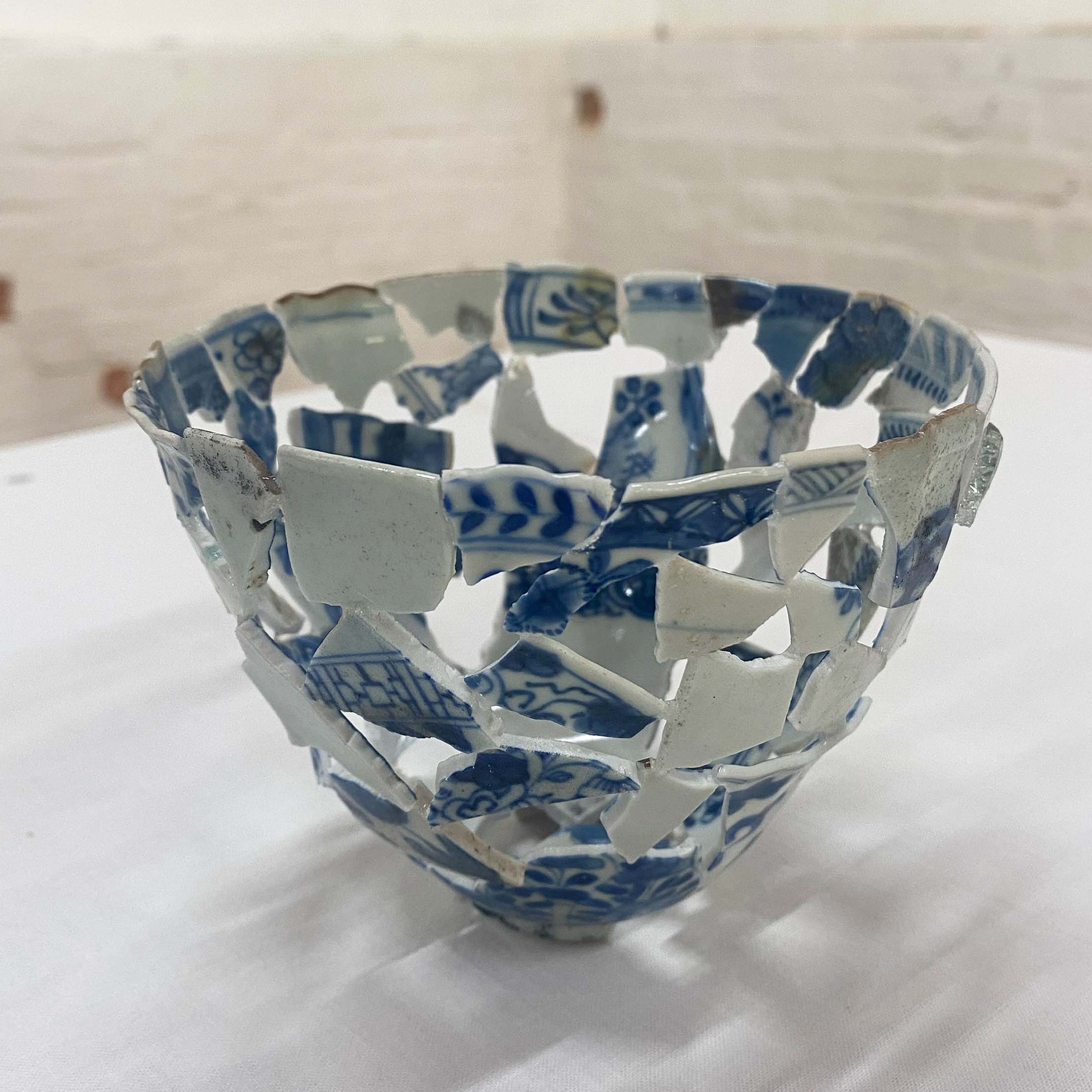 The 'Fire Vase 3' by Tamlin Blake in her 'After the Fire' exhibition, crafted from fractured china plates, representing a resilient beauty and the theme of reflecting history through art at Cape Heritage Hotel.