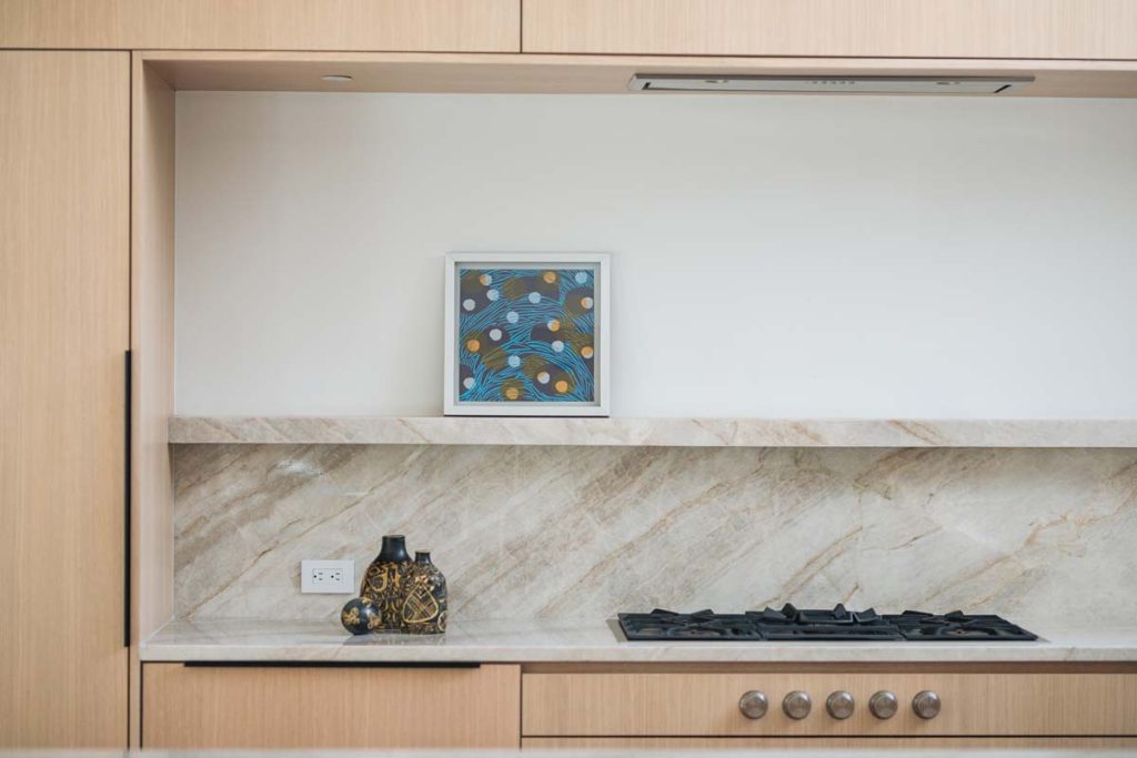 Sleek kitchen in Dissonant House with custom cabinetry, marble countertops, and a skylight that fills the space with natural light, highlighting the home's luxurious and functional design.