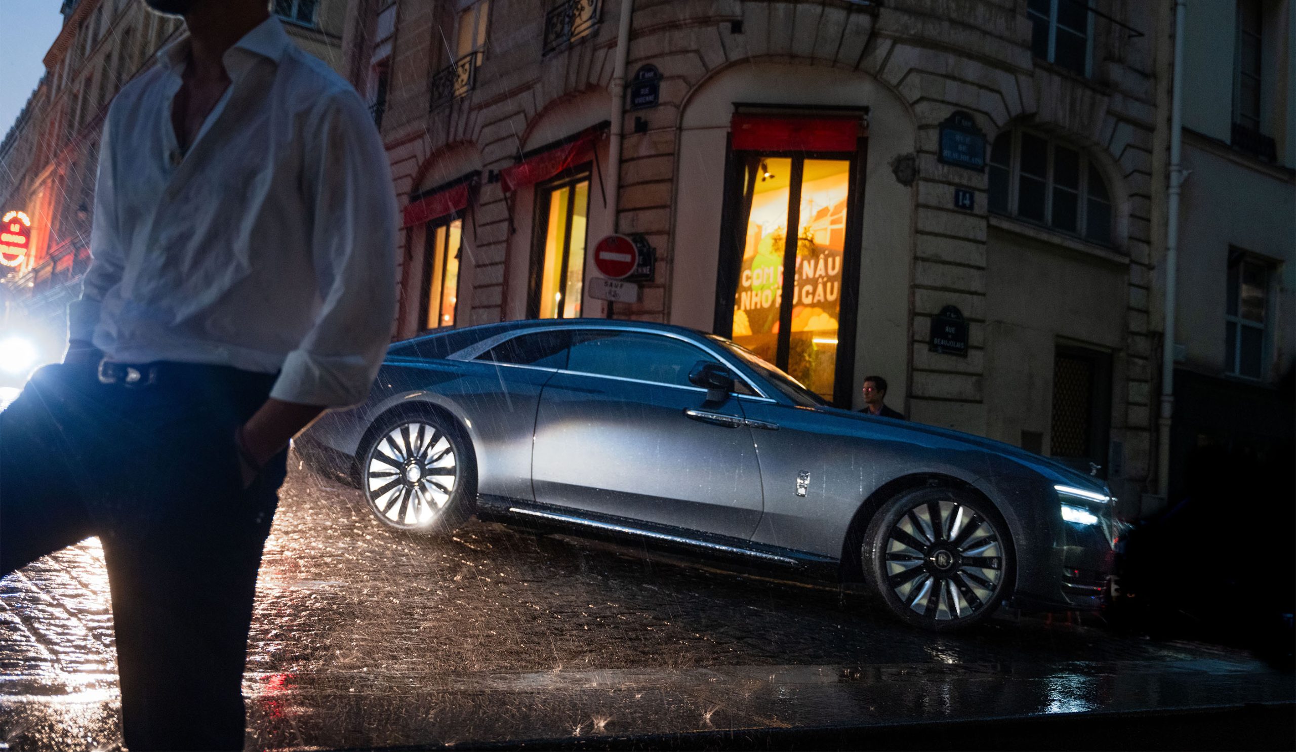 Rolls-Royce Spectre coupe in Paris at night in wet street scene.