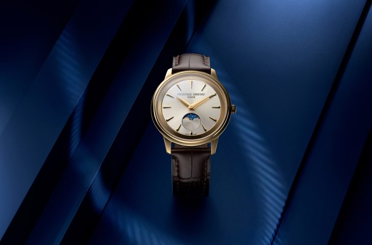 Styled image of the Frederique Constant Classics Moneta Moonphase in yellow gold PVD with a silver dial, black leather strap, and moonphase display.
