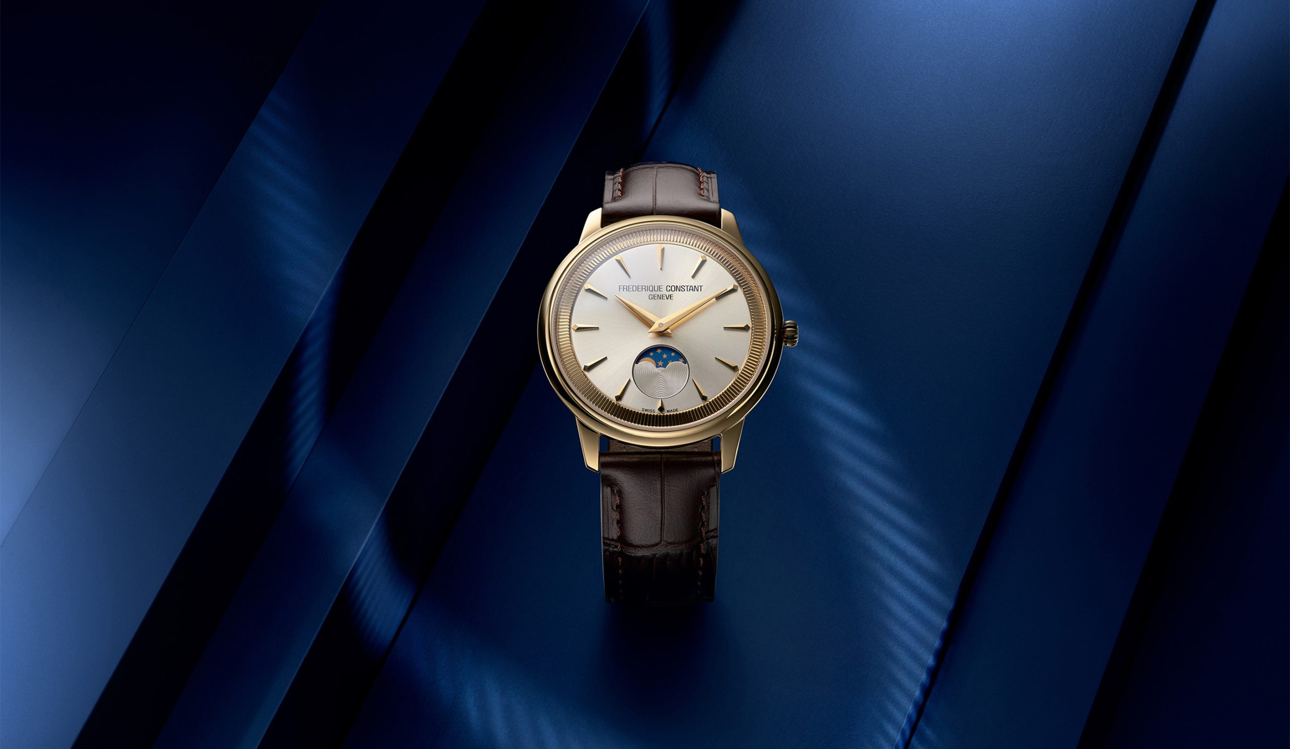 Styled image of the Frederique Constant Classics Moneta Moonphase in yellow gold PVD with a silver dial, black leather strap, and moonphase display.